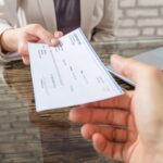 Businesswoman Giving Cheque To Her Colleague