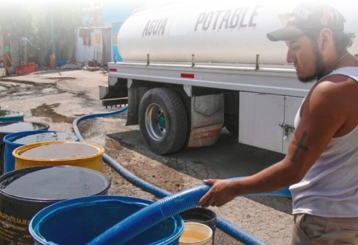Familia en colonia popular almacenando agua ante la falta de suministro regular.