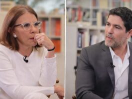 Entrevista censurada: Sabina Berman y Eduardo Verástegui debaten familia, libertad y aborto Dos personas sentadas frente a frente en un espacio tipo biblioteca, conversando durante una entrevista; una mujer viste de blanco y escucha con atención, mientras un hombre con traje gris habla y gesticula suavemente.