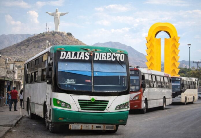 Autobús urbano deteriorado en Torreón con el Cristo de las Noas y el Monumento al Torreón al fondo.