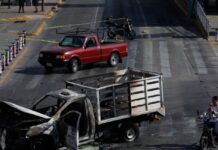 Refuerzan seguridad y medidas preventivas tras operativo contra líder del CJNG Camioneta incendiada en una vialidad urbana acordonada por autoridades, imagen que ilustra los bloqueos y disturbios registrados tras el operativo federal contra el líder del CJNG.