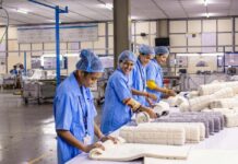 Diputados avalan la jornada de 40 horas; la reforma avanza con consenso histórico Trabajadoras con uniforme industrial azul revisan y doblan piezas textiles en una línea de producción dentro de una planta manufacturera.