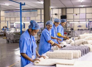 Diputados avalan la jornada de 40 horas; la reforma avanza con consenso histórico Trabajadoras con uniforme industrial azul revisan y doblan piezas textiles en una línea de producción dentro de una planta manufacturera.