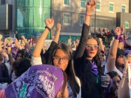 8M en México: por qué marchan las mujeres y qué caminos hay para cambiar la realidad Multitud de mujeres marchando durante el 8M con pañuelos morados y el puño en alto en señal de protesta y solidaridad.