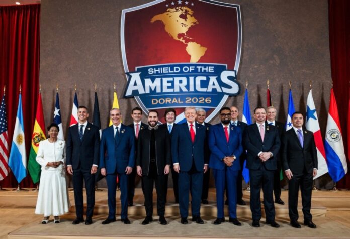 Donald Trump y varios líderes latinoamericanos posan frente al emblema “Shield of the Americas – Doral 2026” con banderas de distintos países del continente detrás.