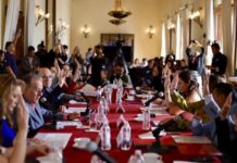 Tras el rechazo de la reforma electoral, el “Plan B” de Sheinbaum busca reducir costos políticos desde los estados y municipios Integrantes del Cabildo de San Luis Potosí levantan la mano durante una votación en una sesión oficial, con micrófonos y documentos sobre una mesa larga cubierta con mantel rojo.