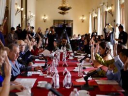 Tras el rechazo de la reforma electoral, el “Plan B” de Sheinbaum busca reducir costos políticos desde los estados y municipios Integrantes del Cabildo de San Luis Potosí levantan la mano durante una votación en una sesión oficial, con micrófonos y documentos sobre una mesa larga cubierta con mantel rojo.