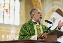 ¿Quién debe predicar en la Iglesia católica? Sacerdote católico predicando desde el ambón durante la homilía en una iglesia, vestido con casulla verde litúrgica.
