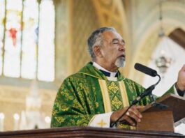 ¿Quién debe predicar en la Iglesia católica? Sacerdote católico predicando desde el ambón durante la homilía en una iglesia, vestido con casulla verde litúrgica.