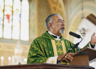 ¿Quién debe predicar en la Iglesia católica? Sacerdote católico predicando desde el ambón durante la homilía en una iglesia, vestido con casulla verde litúrgica.