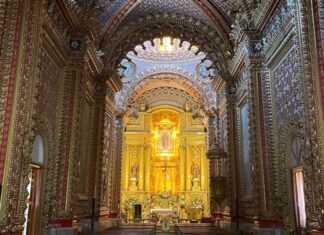 ¿Cómo se construyeron los templos monumentales de México? La historia detrás de su grandeza Interior de un templo barroco en Morelia, Michoacán, con bóvedas y muros completamente decorados, retablos dorados y un altar central iluminado con la imagen de la Virgen de Guadalupe.