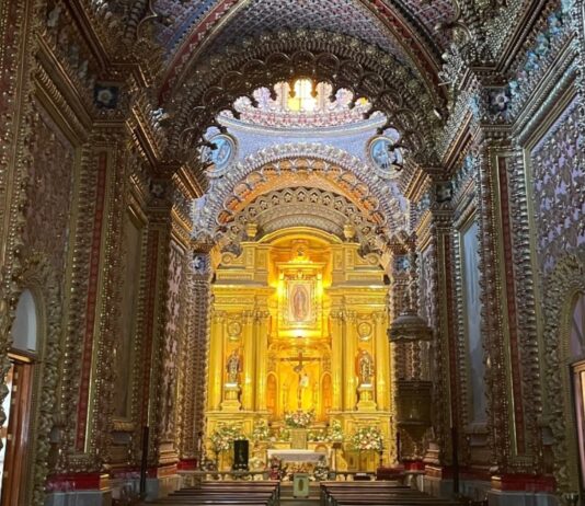 ¿Cómo se construyeron los templos monumentales de México? La historia detrás de su grandeza Interior de un templo barroco en Morelia, Michoacán, con bóvedas y muros completamente decorados, retablos dorados y un altar central iluminado con la imagen de la Virgen de Guadalupe.