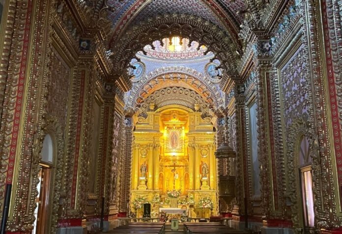 Interior de un templo barroco en Morelia, Michoacán, con bóvedas y muros completamente decorados, retablos dorados y un altar central iluminado con la imagen de la Virgen de Guadalupe.