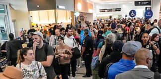 Se paraliza parcialmente gobierno federal de EE.UU. por la falta de un acuerdo presupuestario Multitud de pasajeros haciendo largas filas dentro de un aeropuerto en Estados Unidos, con áreas saturadas y personal limitado, en un contexto de afectaciones operativas por falta de pago a trabajadores federales.