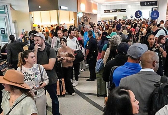 Multitud de pasajeros haciendo largas filas dentro de un aeropuerto en Estados Unidos, con áreas saturadas y personal limitado, en un contexto de afectaciones operativas por falta de pago a trabajadores federales.
