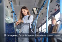 La vida cotidiana bajo presión: por qué sentimos que nunca tenemos tiempo (aunque sí lo tenemos) Mujer de pie dentro de un autobús urbano revisando su reloj, rodeada de otros pasajeros en un entorno cotidiano de transporte público.