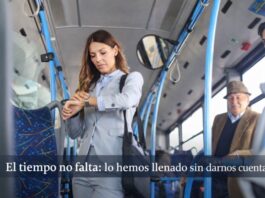 La vida cotidiana bajo presión: por qué sentimos que nunca tenemos tiempo (aunque sí lo tenemos) Mujer de pie dentro de un autobús urbano revisando su reloj, rodeada de otros pasajeros en un entorno cotidiano de transporte público.
