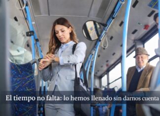 La vida cotidiana bajo presión: por qué sentimos que nunca tenemos tiempo (aunque sí lo tenemos) Mujer de pie dentro de un autobús urbano revisando su reloj, rodeada de otros pasajeros en un entorno cotidiano de transporte público.