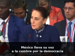 Sheinbaum en Barcelona: una voz que habla desde México ante el mundo Claudia Sheinbaum habla en un foro internacional en Barcelona, sentada frente a un micrófono, con la bandera de México visible a un costado.