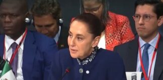 Sheinbaum en Barcelona: una voz que habla desde México ante el mundo Claudia Sheinbaum habla en un foro internacional en Barcelona, sentada frente a un micrófono, con la bandera de México visible a un costado.