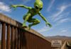 La confusión de los “aliens”: una palabra cambia por completo una noticia Ilustración conceptual de un extraterrestre verde brincando sobre un muro fronterizo en una zona desértica, simbolizando la confusión entre los términos “alien” como extraterrestre y “alien” como extranjero en el lenguaje político estadounidense.