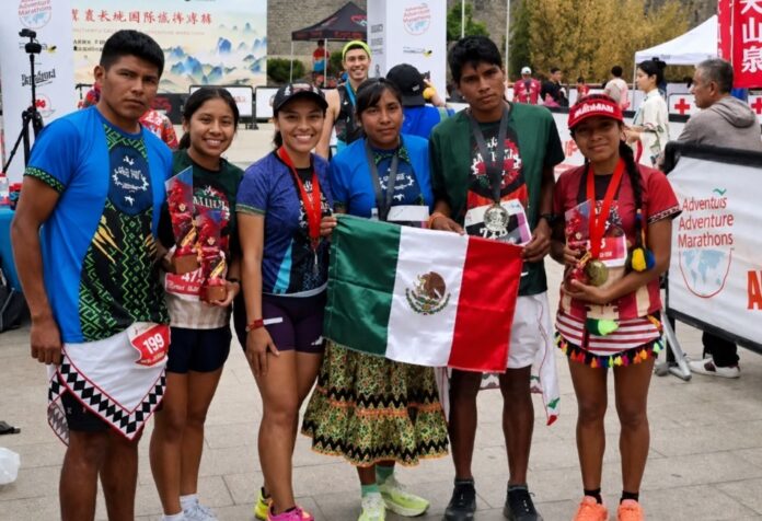 Atletismo indígena Grupo de atletas indígenas mexicanos posa con medallas y la bandera de México tras competir en el Maratón de la Gran Muralla China.