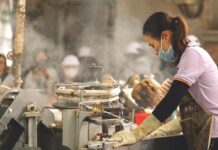 México registra una de las tasas de desempleo más bajas del mundo Mujer trabajando en una línea de producción industrial mientras opera maquinaria en un entorno de manufactura, con vapor y equipo de trabajo al fondo.