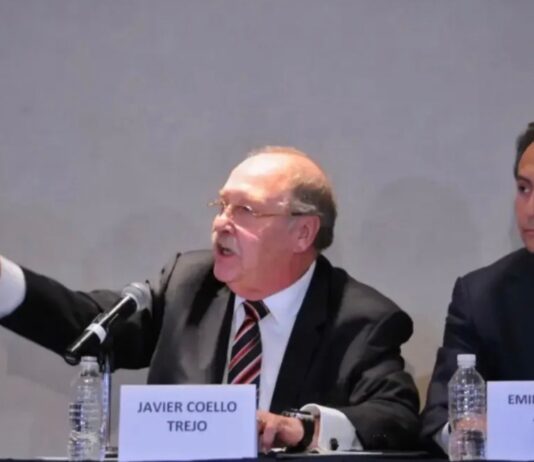 Francisco Javier Coello Trejo, el “Fiscal de Hierro” del México represor Francisco Javier Coello Trejo participa en una conferencia pública sentado junto a Emilio Lozoya Austin, exdirector de Pemex, frente a micrófonos y mesas de exposición.