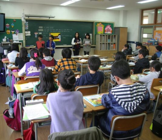 La educación nunca ha sido neutral Alumnos de educación básica en un salón de clases mexicano atienden una exposición frente al pizarrón, donde se observan materiales educativos, mensajes de convivencia escolar y la bandera nacional.
