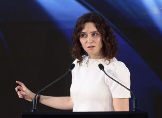 Ayuso regresa a España y describe un México que millones de mexicanos no reconocen Isabel Díaz Ayuso durante una conferencia en México, frente a dos micrófonos y con fondo oscuro iluminado en tonos azules.