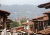 México también se descubre caminando despacio Calles de un Pueblo Mágico mexicano con techos de teja y una iglesia al fondo entre montañas y neblina.