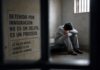 El aumento de suicidios en centros migratorios de Estados Unidos enciende alarmas sobre salud mental y trato humanitario Persona sentada sola en una celda de detención, con la cabeza inclinada y actitud de angustia, observada a través de barrotes. La imagen simboliza el aislamiento, la incertidumbre y los desafíos de salud mental que enfrentan algunos migrantes bajo custodia.
