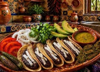 Los tacos de frijol: una comida sencilla que en realidad alimenta muy bien Plato de barro con tacos de frijol acompañados de aguacate, nopales asados, salsa verde, jitomate y cebolla en una cocina de estilo mexicano tradicional.
