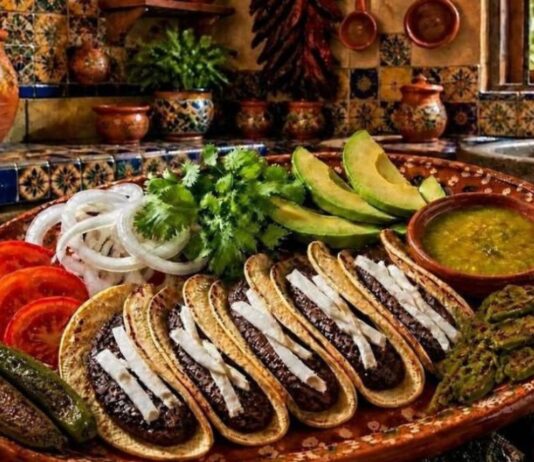 Los tacos de frijol: una comida sencilla que en realidad alimenta muy bien Plato de barro con tacos de frijol acompañados de aguacate, nopales asados, salsa verde, jitomate y cebolla en una cocina de estilo mexicano tradicional.
