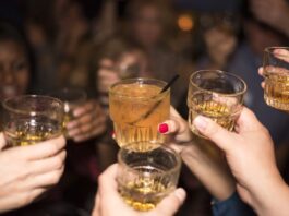 Jóvenes, alcohol y nuevas formas de divertirse Grupo de jóvenes brindando con bebidas alcohólicas durante una reunión nocturna, imagen que ilustra un artículo sobre el ocio juvenil y el consumo de alcohol en España y México.