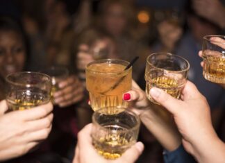Jóvenes, alcohol y nuevas formas de divertirse Grupo de jóvenes brindando con bebidas alcohólicas durante una reunión nocturna, imagen que ilustra un artículo sobre el ocio juvenil y el consumo de alcohol en España y México.