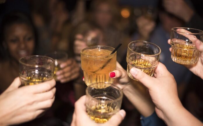 Grupo de jóvenes brindando con bebidas alcohólicas durante una reunión nocturna, imagen que ilustra un artículo sobre el ocio juvenil y el consumo de alcohol en España y México.