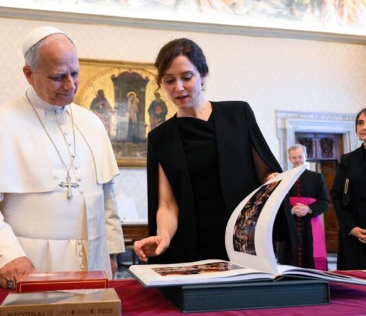 España se prepara para recibir al Papa León XIV El Papa León XIV observa un libro junto a Isabel Díaz Ayuso durante una reunión oficial, mientras varias personas acompañan el encuentro en una sala institucional.