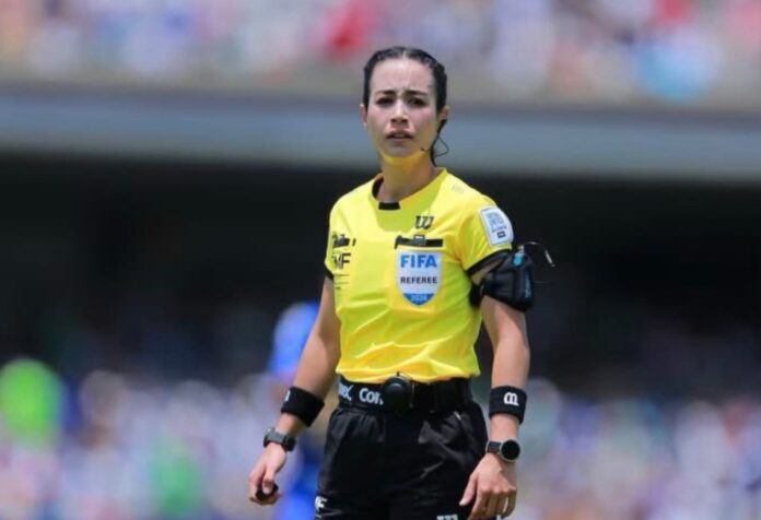 Katia Itzel García Katia Itzel García, árbitra mexicana con uniforme amarillo de la FIFA, observa una jugada durante un partido en un estadio lleno de aficionados.