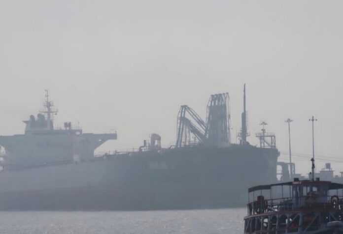 Ormuz, guerra de narrativas Buque petrolero de gran tamaño navegando en aguas con neblina cerca de una terminal marítima. La imagen ilustra la importancia estratégica del transporte de hidrocarburos en el Estrecho de Ormuz durante las negociaciones entre Estados Unidos e Irán.