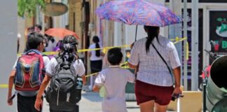 Detectar a tiempo el cáncer de piel puede salvar vidas: hasta 95% de los casos pueden curarse Madre y tres niños caminan bajo el sol en una calle urbana; uno de los adultos utiliza sombrilla para protegerse de la radiación solar durante una jornada de altas temperaturas.