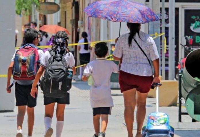 Protegerse del sol Madre y tres niños caminan bajo el sol en una calle urbana; uno de los adultos utiliza sombrilla para protegerse de la radiación solar durante una jornada de altas temperaturas.