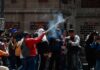 La CNTE inicia huelga nacional y reabre el debate sobre la educación de los niños Manifestantes participan en una protesta en el Zócalo de la Ciudad de México. Una persona sostiene un artefacto que emite humo mientras periodistas y fotógrafos documentan la movilización frente a un edificio histórico.