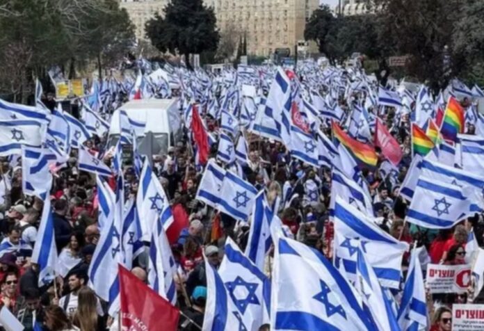 Multitud de manifestantes con banderas de Israel durante una protesta masiva en una avenida de una ciudad israelí.
