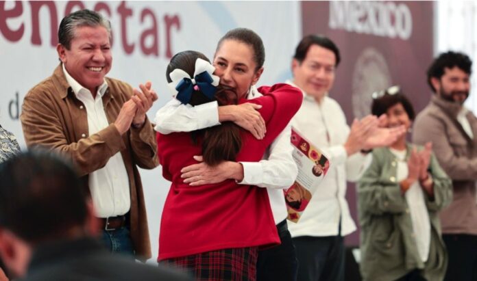Beca Gertrudis Bocanegra La presidenta Claudia Sheinbaum abraza a una estudiante durante un evento de entrega de becas en Zacatecas, acompañada por autoridades federales y estatales.