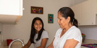 La costumbre que estamos perdiendo… y que puede cambiar una familia Una mujer y una adolescente lavan los platos juntas en la cocina de su hogar mientras conversan y sonríen, reflejando la importancia de compartir tiempo en familia.
