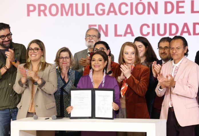 Ley de Cuidados de la Ciudad de México Clara Brugada sostiene el decreto de la Ley del Sistema de Cuidados durante su promulgación, acompañada por integrantes del gobierno y organizaciones civiles en la Ciudad de México.