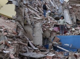 Delcy Rodríguez anuncia plan de recuperación tras los sismos y pide levantar sanciones a Venezuela Mujer de pie entre los escombros de edificios derrumbados por los terremotos en Venezuela, con estructuras colapsadas y labores de recuperación en el lugar.