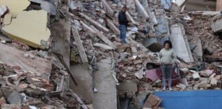 Delcy Rodríguez anuncia plan de recuperación tras los sismos y pide levantar sanciones a Venezuela Mujer de pie entre los escombros de edificios derrumbados por los terremotos en Venezuela, con estructuras colapsadas y labores de recuperación en el lugar.