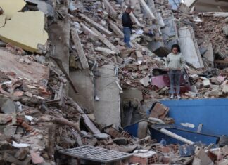 Delcy Rodríguez anuncia plan de recuperación tras los sismos y pide levantar sanciones a Venezuela Mujer de pie entre los escombros de edificios derrumbados por los terremotos en Venezuela, con estructuras colapsadas y labores de recuperación en el lugar.